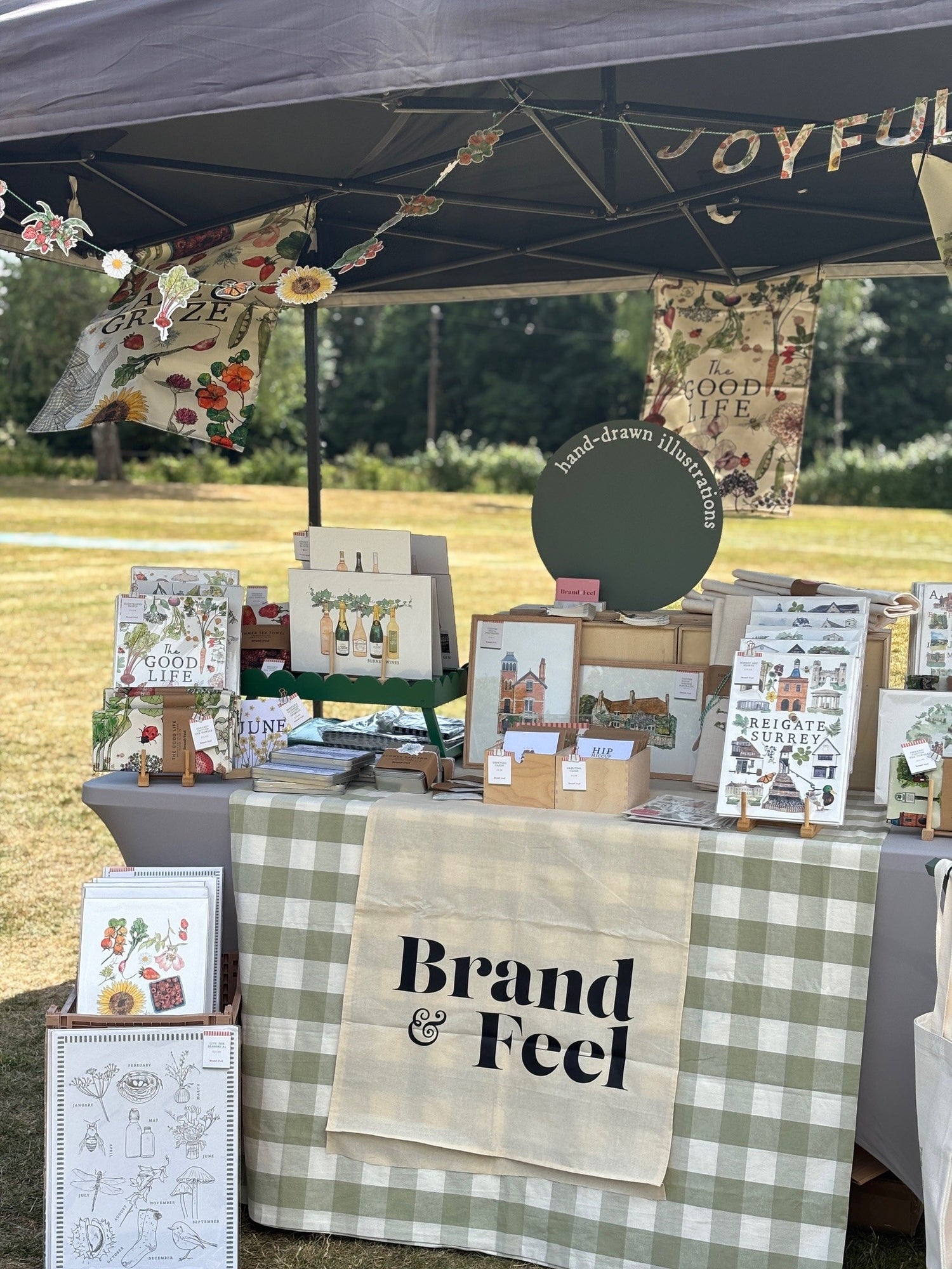 Outdoor market stall with country home wall art prints and a sign reading 'Brand & Feel'.